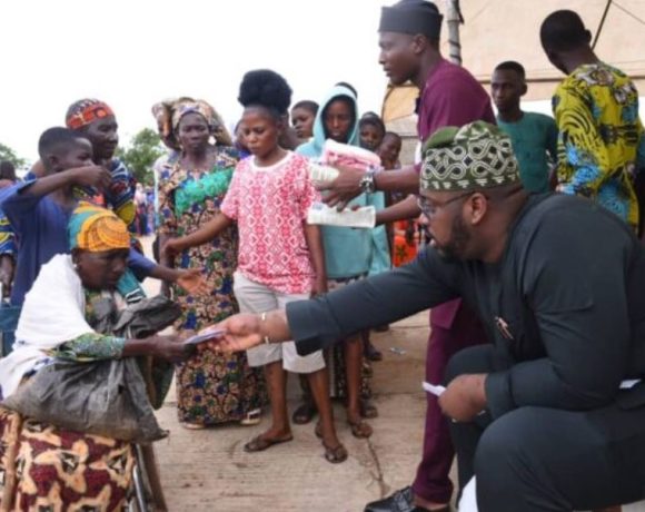 Honourable Abdulrasheed Kashamu distributing cash and food items to a crowd at his residence in Ijebu Igbo during the Eid-el Kabir celebration.